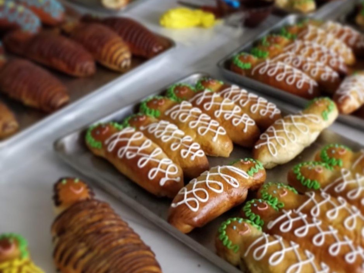 Bandejas con guaguas de pan recién horneadas y decoradas con glaseado blanco, verde y amarillo